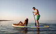 © fotofabrika - Couple of tourists young man and woman having fun paddleboarding at sea