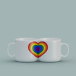 3D illustration of two white matching mugs with a rainbow heart on a grayish-blue background