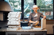 Pizzeria worker folds foil into pizza box. Catering kitchen work.