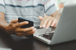 © khunkornStudio - man hand using smart phoneand laptop on table at home, searching information  browsing the internet on web, work from home.Business shopping online concept