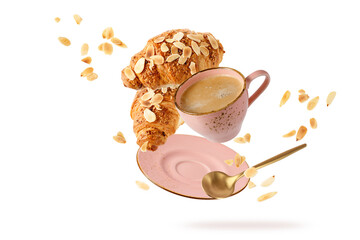 Fresh baked almond  breakfast croissants  with nuts flakes crumbs, pink vintage cup of hot coffee and golden spoon flying isolated on white