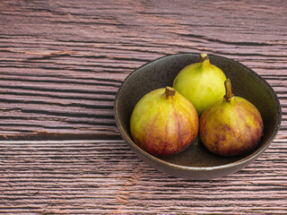 Wall Mural - Top view of ripe figs fruit in a bowl on a wooden table. Space for text. High Vitamins fruit. Close-up photo. Healthy fruits and healthcare concept