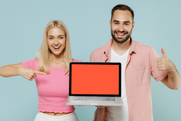 Young couple two friends family man woman in casual clothes hold use work on laptop pc computer blank screen workspace area show thumbup together isolated on pastel plain light blue background studio