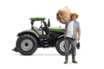 Sticker - Full length portrait of a farmer carrying a sack and standing in front of a tractor