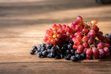 Grapes on a wooden table. Fresh branch of red grapes with leaves