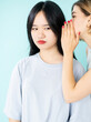 © golubovy - Blaming gossip. Teenager intrigue. Spreading rumors. Conspirator caucasian young women whispering secret information on ear to disbelief asian friend isolated blue.