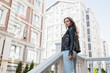 © LIGHTFIELD STUDIOS - low angle view of pretty young woman in black leather jacket standing on urban street in europe