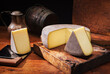 Traditional aged mountain cheese of the Alps offered as loaf and piece at a rustic wooden chalet