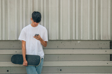 Poster - teenage boy with mobile phone and skateboard on the street