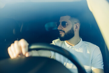 Front view, young handsome man looking straight while driving a car