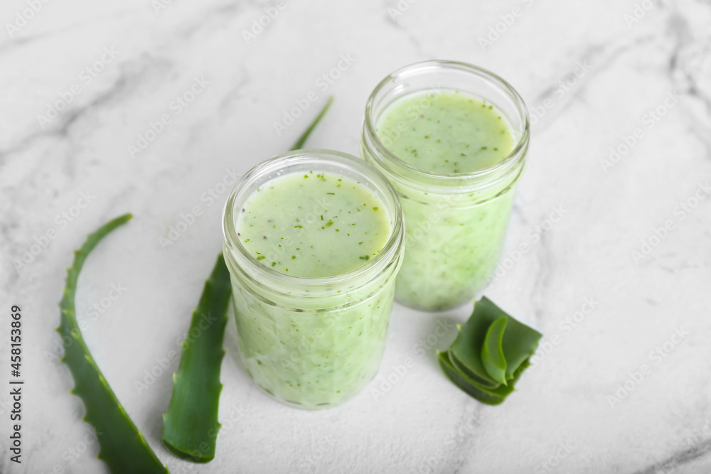 Jars of healthy aloe juice on white background