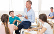 © JackF - Friendly male teacher discussing with teen students in classroom at school..