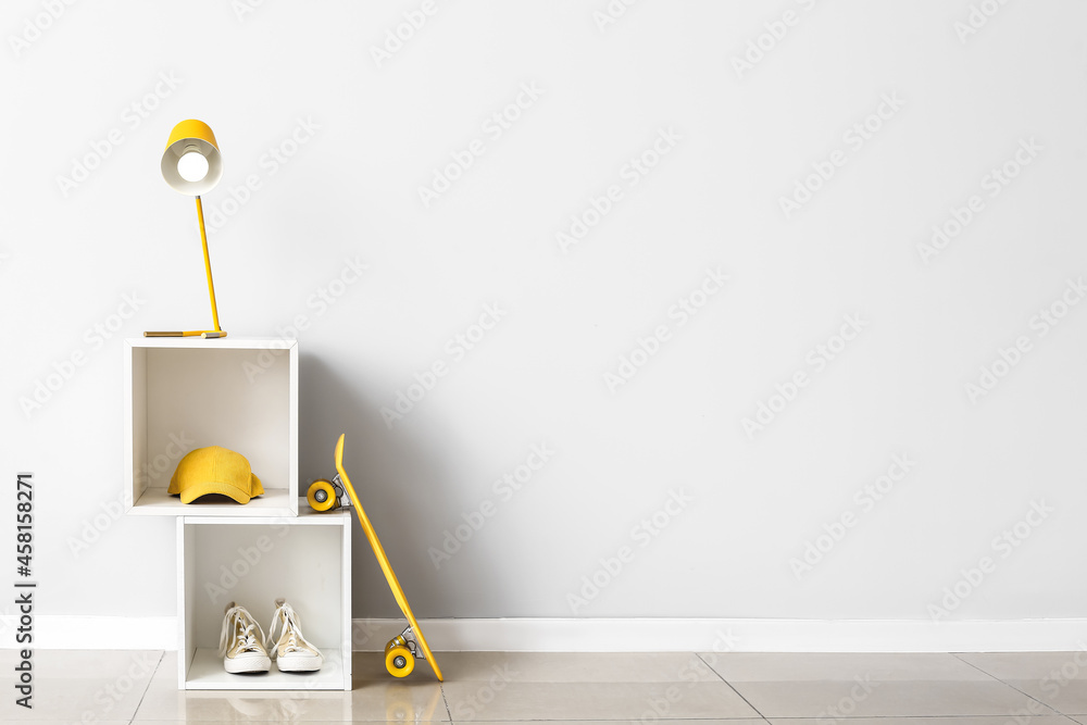 Modern lamp on shelf near white wall