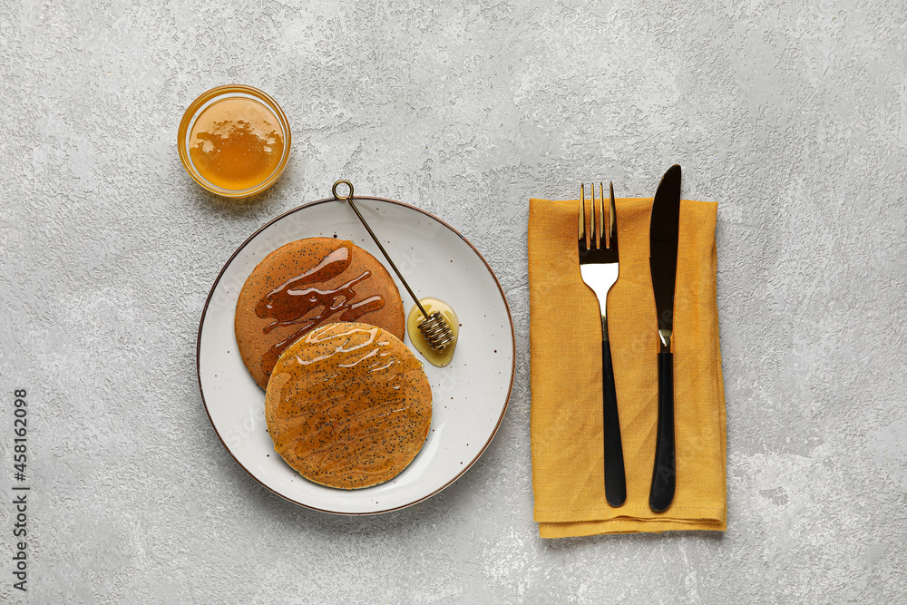 Plate of tasty pancakes with honey on light background