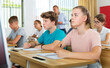 © JackF - Teen boys and girls sitting at desk in classroom full of pupils during lesson
