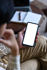 Wall Mural - Young Asian man sitting at workplace and using mobile phone.