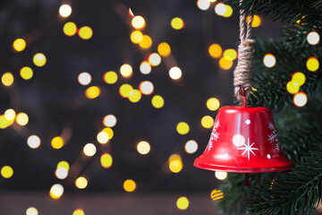 Wall Mural - Christmas composition with a red bell on fir tree on background garland lights.