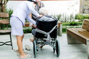 Pensioner sitting in wheelchair, male nurse supporting old patient at clinic