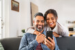 © Rido - Happy indian couple using smartphone at home