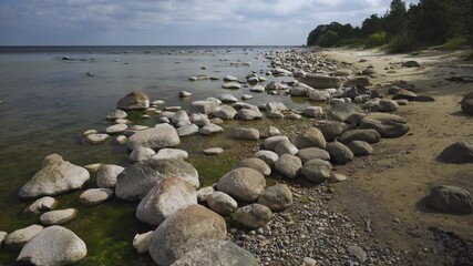 Wall Mural - Large stones on the Baltic Sea beach in Latvian Kurzeme. White clouds over the blue sea to the horizon. Sandy beach with coarse sand in early autumn.