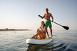 © fotofabrika - Couple of tourists young man and woman having fun paddleboarding at sea