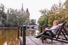 Young Caucasian Woman Sitting On Jetty Next To Vajdahunyad Castle Lake Budapest
