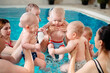 © davit85 - A group of mothers with their young children in a children's swimming class with a coach.