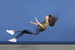 © Lustre Art Group  - Full-length horizontal image of young girl falling isolated over blue background. Dreamy levitation