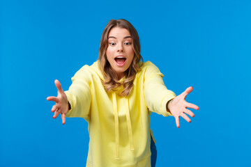 Wall Mural - Girl trying to catch somthing, look focused and amused playing with kids, stretching hands and lean forward to read object with concentrated expression, standing blue background