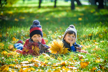 Wall Mural - Beautiful boy, little child laying with a lot of yellow autumn leaves in park. Kid boy having fun on sunny warm october day. Season, children, lifestyle concept