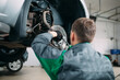 © davit85 - Car lifted in automobile service for fixing, worker repairs the wheel,