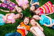 © davit85 - A group of children lying on the green grass in the Park. The interaction of the children.