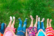 © davit85 - Children lying on green grass in park on a summer day with their legs lifted up to the sky.