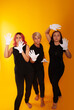 © Marina Chernivetskay - women in white gloves in the image of mimes actress play acting on a yellow background