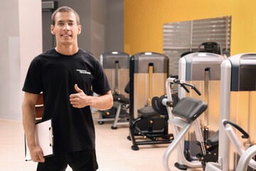 Poster - Portrait of personal trainer with clipboard in modern gym