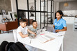© Drobot Dean - Black woman and her sons using gadgets while having breakfast at home