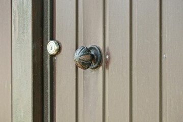 Canvas Print - one round black iron door handle on brown metal door outside