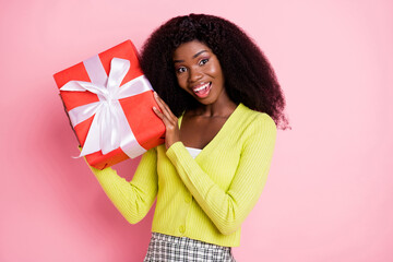 Wall Mural - Portrait of impressed cheerful dark skin lady hands hold giftbox near head toothy smile isolated on pink color background