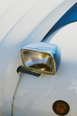 Canvas Print - Vertical shot of the headlight of a light blue vintage car parked outdoors