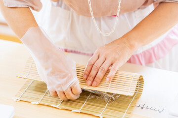 Wall Mural - 料理教室で巻き寿司を作る女性の手元