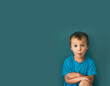 A small surprised boy stands on a green isolated background, selective focus, a place for text