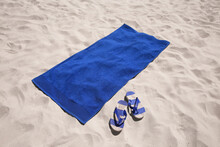 Flip Flops And Blue Beach Towel On Sand