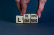 Lifelong learning symbol. Businessman turns wooden cubes with concept words 'Lifelong learning' on a beautiful grey background. Copy space. Business, educational and lifelong learning concept.