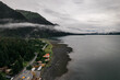 Aerial shot of a foggy morning over the rural town surrounded by lake and mountains in Alaska