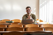 © BalanceFormCreative - Portrait of young male university student sitting in classroom and preparing for lecture. Educational concept.