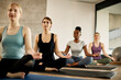 © Drazen - Group of athletic women practice Yoga in lotus pose during exercise class at health club.
