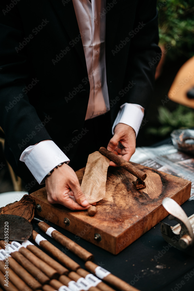 roll of tobacco leaves man rolling tobacco leaf into a cigar Stock Photo