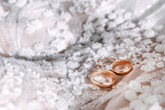 wedding gold rings with diamonds lie on the bride's dress