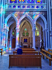 Wall Mural - Old woman praying in the beautiful interior of the basilica of Pontmain.