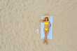 © New Africa - Woman sunbathing on beach towel at sandy coast, aerial view. Space for text
